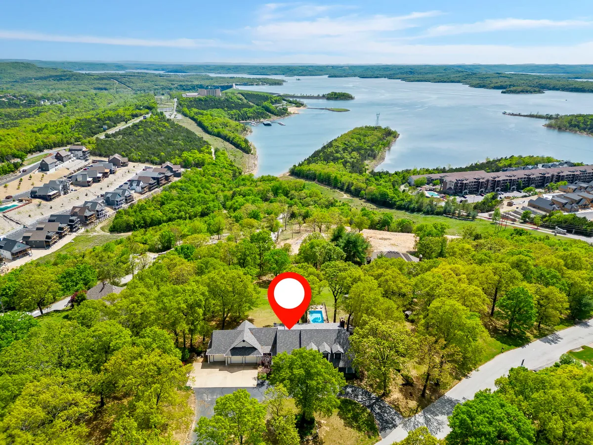 This exterior shot prominently features the house, its swimming pool, lush surrounding greenery, and a clear view of the lake beyond. The tranquil setting is accentuated by the golden hues of sunset, inviting outdoor relaxation and appreciation of nature.