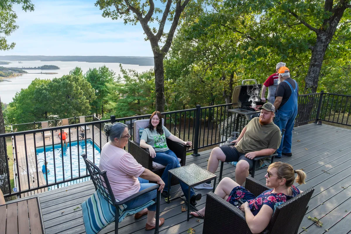 A cheerful group gathers near the pool and grill with the lake in the background. People are barbecuing, swimming, and socializing, capturing the joyful, communal spirit of the outdoor spaces. Pet-friendly grounds and lush greenery complete the scene.